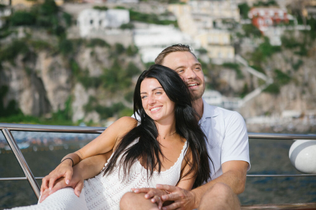 Woman laughing on boat after proposal, wind in her hair, golden hour light