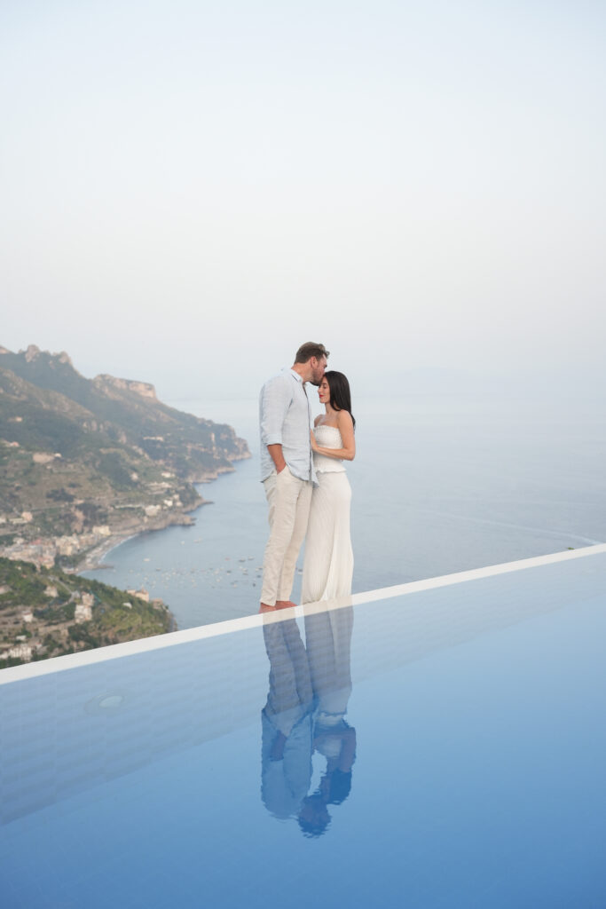 Couple standing beside an infinity pool during sunset overlooking the Amalfi Coast